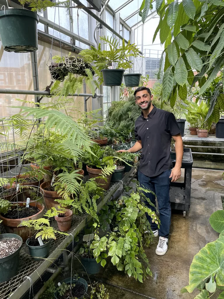 A man poses for a photo in the greenhouse