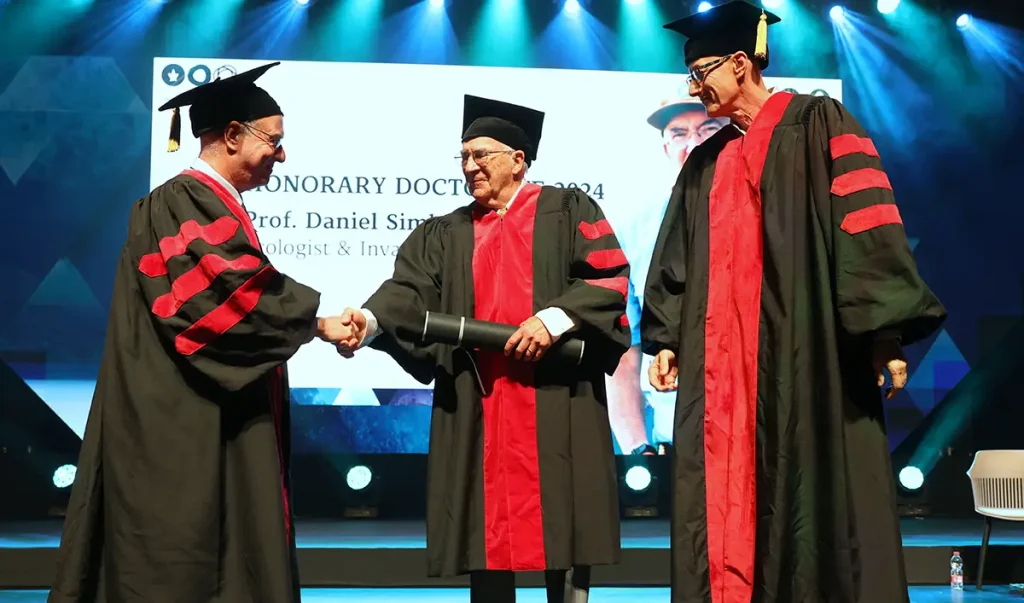 Tel Aviv President Ariel Porat, from left, congratulates University of Tennessee Professor Daniel Simberloff, along with TAU Rector Mark Shtaif on stage while in black and red regalia